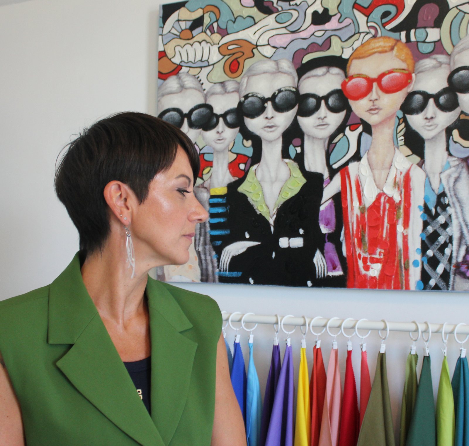 Audrey Fisicaro, en veste vert olive, devant son portant de foulards de couleurs